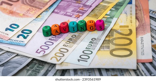 Small cube text SAVING on dollar euro bills background. Finance concept. Wealth