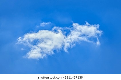 A small cumulus cloud. Clouds flowing lazily like cottony fibers against a clear, serene blue background. The sky speaks of calm, peace, and silence.