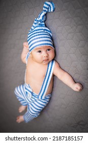 Small Cute Babe Lying In Funny Hat. Young Adorable Newborn In Bedroom.