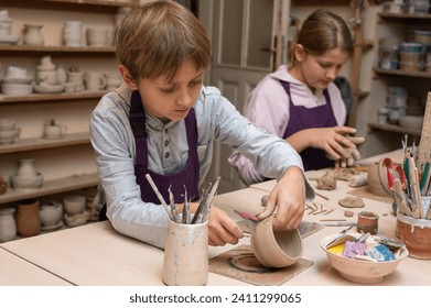 small, cute, emotional boy and fair-haired girl sculpting from clay in a pottery workshop, clay crafts and art, children's creativity, art education, pottery - Powered by Shutterstock