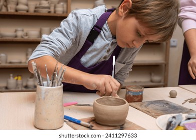 small, cute, emotional boy sculpts from clay in a pottery workshop, craft and clay art, children's creative activity, art education - Powered by Shutterstock