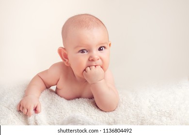 Small cute funny baby infant teething with face expression hands and fingers in mouth sore gums soothe
