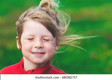 small cute girl portrait. adorable blond kid close up. cheerful preschooler enjoying vacation outside on windy day. 