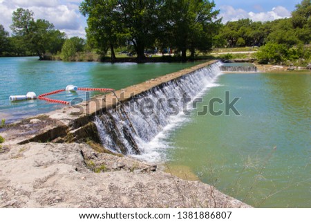 a small dam filled to the top in the Blanco State Park in Texas