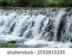 small dam on a river, foaming water coming over a small waterfall from a dam.