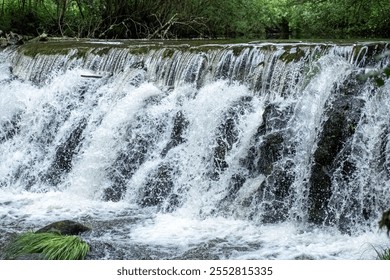 small dam on a river, foaming water coming over a small waterfall from a dam. - Powered by Shutterstock