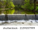 The small dam or spillway above the falls on the Chagrin River in Chagring Falls, Ohio, on a tranquil spring morning