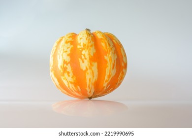 Small Decorative Pumpkin With Orange Spots On A Light Background