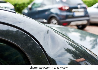 A Small Dent In The Coating Of A Black Car