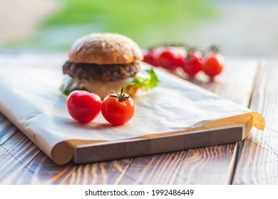 Small depth of field. Soft focus. Burger made it at home. Next to it are red tomatoes on a branch. Close-up