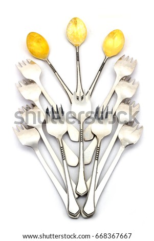 Small dessert spoons and forks lined with a beautiful pattern on a white background