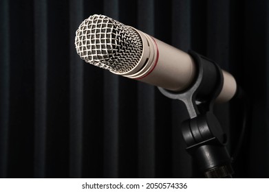 Small Diaphragm Condenser Microphone On Stand In Front Of Acoustic Tile In Recording Studio