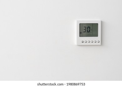 Small Digital Climate Control Thermostat With Six Buttons On White Wall Of Hotel Or Office Indicating Current Temperature, Copy Space For Text