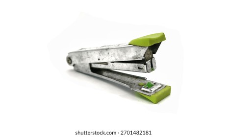 a small, dirty and rustic portable stapler with a metallic body and neon green plastic accents isolated on white background