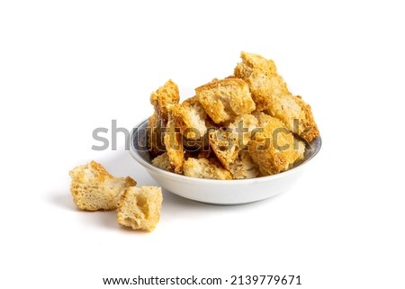 A small dish of toasted seasoned garlic and Parmesan soup or salad croutons isolated on white