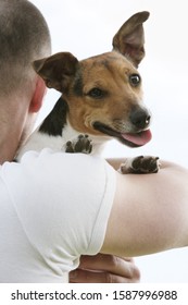 Small Dog Looking Over Man's Shoulder Outdoors