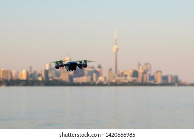 Small drone flying hanging in the air with Toronto City skyline out of focus in the background. Selective focus, blurred background. New technology, devices, gadgets concept. Space for copy.