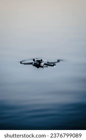 a small drone hovering above the surface of a still lake