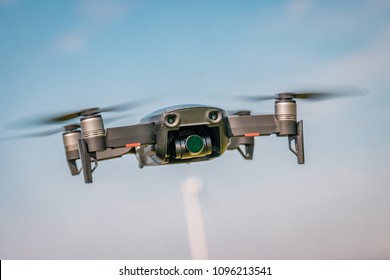 Small drone isolated in the sky on a summer day with a blue sky on the background. Black mini drone flying