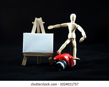 Small dummy red camera and art canvas on easel. Here you can write a message. - Powered by Shutterstock