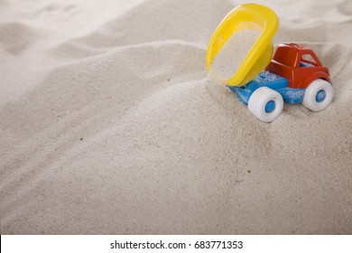 Small Dump Truck Empties Sand. Miniature. Children Play In The Sand. Sand Therapy. Psychology And Construction.