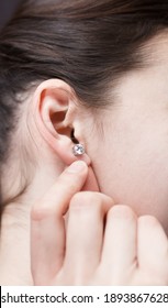 Small Earring in the ear. Hand near the earlobe. Brown-haired woman. Female profile - Shutterstock ID 1893867628