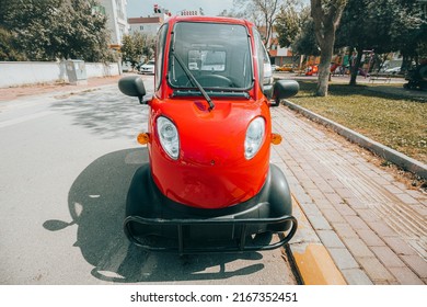 Small electric car parked near sidewalk at city street. Modern eco urban transport