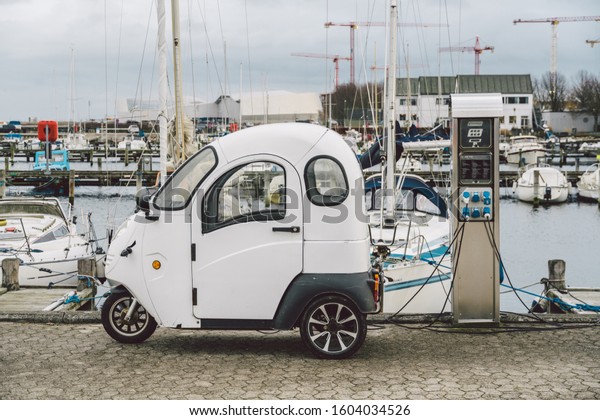 small electro car charging in street near\
seafront in Copenhagen, Denmark. Electric car charging battery.\
alternative environmental energy for car. Environmental protection.\
Contraction global\
warming