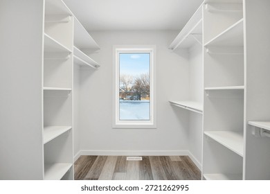 Small, empty walk in closet with a window. The window is frosted and the closet is white