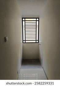 A small, enclosed space with a barred window allowing light and airflow. The minimalistic design suggests it could be a ventilation area or a utility corner for household tasks.