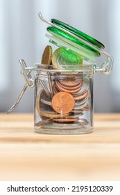 Small Euro Cents Coins Do Not Fit In A Glass Jar On A Neutral Background, Close-up, Selective Focus. A Concept For Business And Finance.