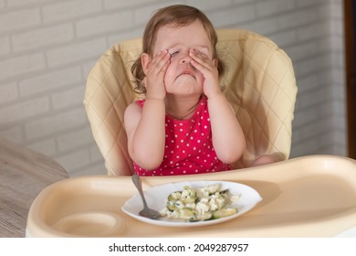 A Small European Child Does Not Want To Eat Vegetable And Egg Lasagna And Rubs His Eyes With His Hands. The Kid Is Naughty Before Eating.