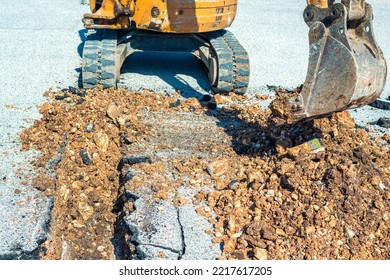 Small Excavator With Narrow Bucket In Action For The Construction Of A Channel On A Building Site