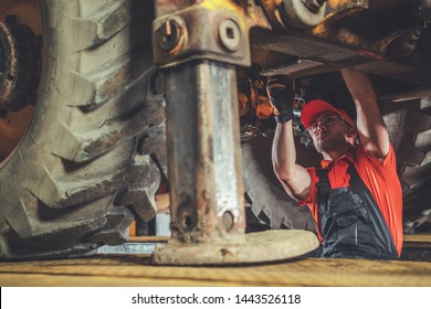 Small Excavator Repair And Maintenance. Caucasian Heavy Equipment Mechanic Trying To Find An Issue. Industrial Theme.