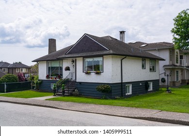 Small Family House With Green Lawn In Front.  Average Residential House On Cloudy Day In British Columbia