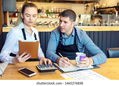 Small Family Restaurant Owners Discussing Finance Calculating Bills And Expenses Of New Small Business – Stressed Man And Woman Going Through Paperwork Together In Cofee Shop