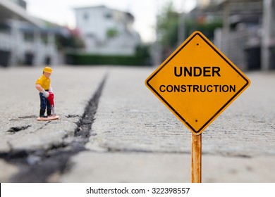 small figure of a man digging concrete street with Under Construction message.