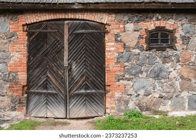 Small figured window and a large closed wooden gate leading into the stone barn. From the series Doors of the World.