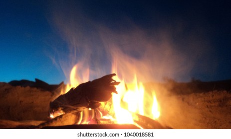 A small fire on the beach on a cool summer evening.                                - Shutterstock ID 1040018581