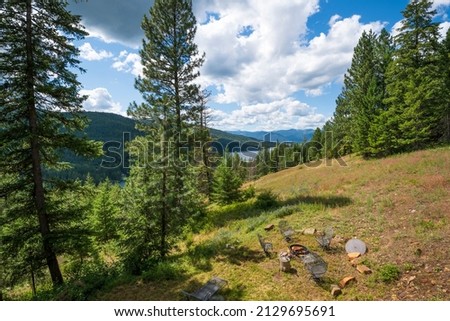 A small fire pit with wood surrounded by chairs on a hillside in the remote mountains overlooking Lake Pend Oreille near Sandpoint, Idaho.
