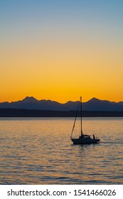 A small fisherman's boat surrounded by the Olympic Mountains and the Seattle sunset
