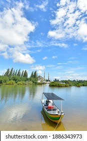 Small Fishing Boat Floats On The Terengganu River And The Crystal Mosque In A Background