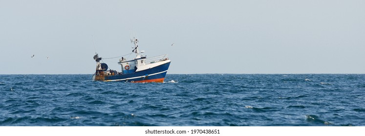 Small fishing boat sailing in an open Mediterranean sea, close-up. A view from the yacht. Leisure activity, sport and recreation, food industry, traditional craft, environmental damage concepts - Powered by Shutterstock