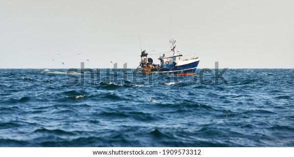 Small fishing boat sailing in an open\
Mediterranean sea, close-up. A view from the yacht. Leisure\
activity, sport and recreation, food industry, traditional craft,\
environmental damage\
concepts