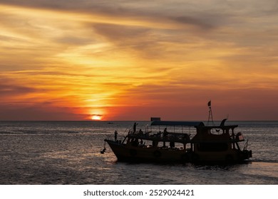 Small fishing boat is silhouetted against the vibrant orange red sky at fiery sunset near Duong Dong on Phu Quoc island, Vietnam, South East Asia. Dramatic peaceful atmosphere in Gulf of Thailand - Powered by Shutterstock