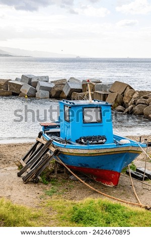 Small fishing boat stopped on the beach of the Strait of Messina between the towns of Ganzirri and Capo Peloro in the municipality of Messina. Area affected by the construction of the Bridge.