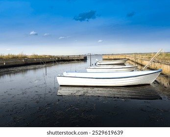 Small fishing boats anchored to shore on a low tide in Denmark - Powered by Shutterstock