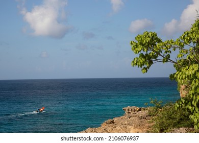 Small Fishing Dinghy Sailing Along The Island Cliff Coast To His Fishing Spot