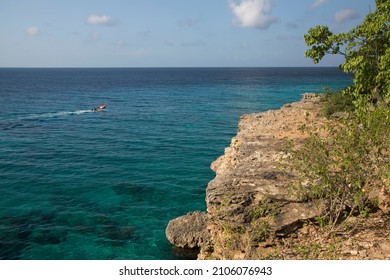 Small Fishing Dinghy Sailing Along The Island Cliff Coast To His Fishing Spot