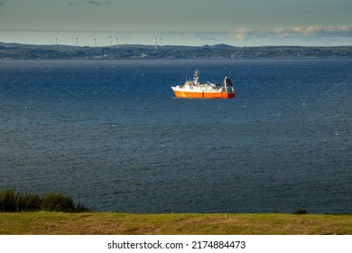 Small Fishing Ship With Red Hull In The Ocean. Galway Bay, Ireland. Food Industry And Supply Concept. Cloudy Sky And Dark Color Water Surface.